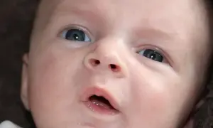 Niebieskie oczy niemowlaka, które właśnie zaczyna widzieć, patrzą z zaciekawieniem na świat.