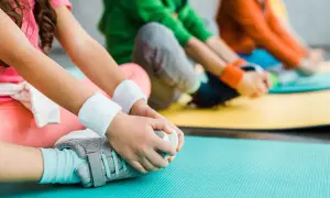 Dzieci ćwiczą, dotykając stóp. Delikatne ruchy mogą pomóc w przypadku hipermobilności stawów u dzieci.