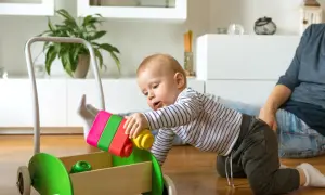8-miesięczne dziecko bawi się kolorowymi klockami, wkładając je do drewnianego wózka. Radość z zabawy z maluchem.