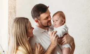 Uśmiechnięta mama i tata patrzą na swoje dziecko, które właśnie zaczyna rozpoznawać twarze.