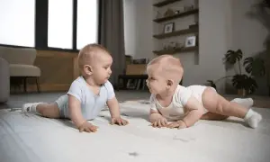 Dwa niemowlaki na macie, każde w body, patrzą na siebie. To ich pierwszy **5 skok rozwojowy**!