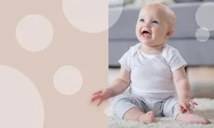 Uśmiechnięte dziecko w białej koszulce i pasiastych spodenkach siedzi na dywanie. To obrazek, który może pomóc w nauce, jak nauczyć dziecko siadać.