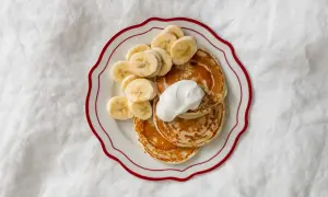 Pyszne placuszki bananowe dla dzieci, udekorowane plasterkami banana i kleksem śmietany. Idealne na śniadanie!