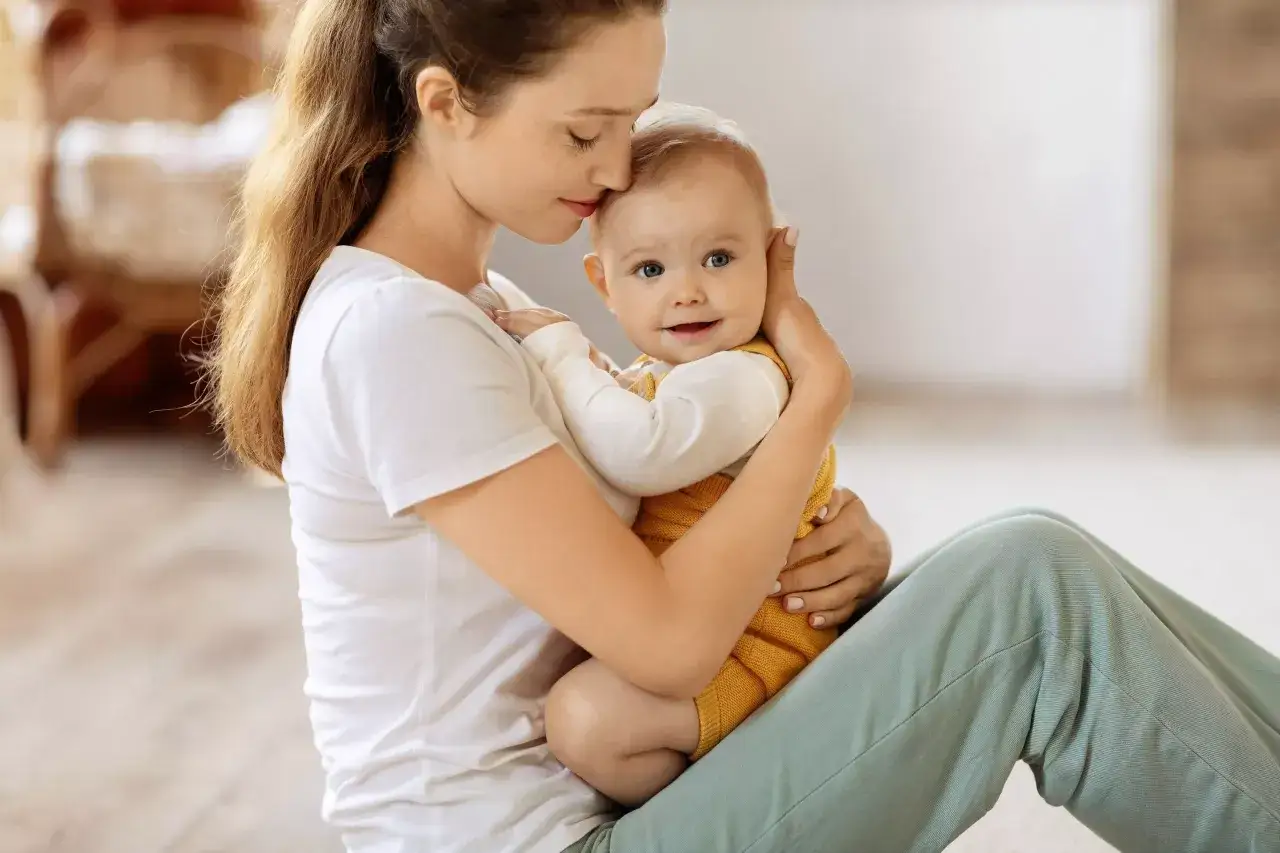 Mama tuli noworodka, czule całuje go w czoło. Dziecko ma 2 tygodnie i przechodzi skok rozwojowy.