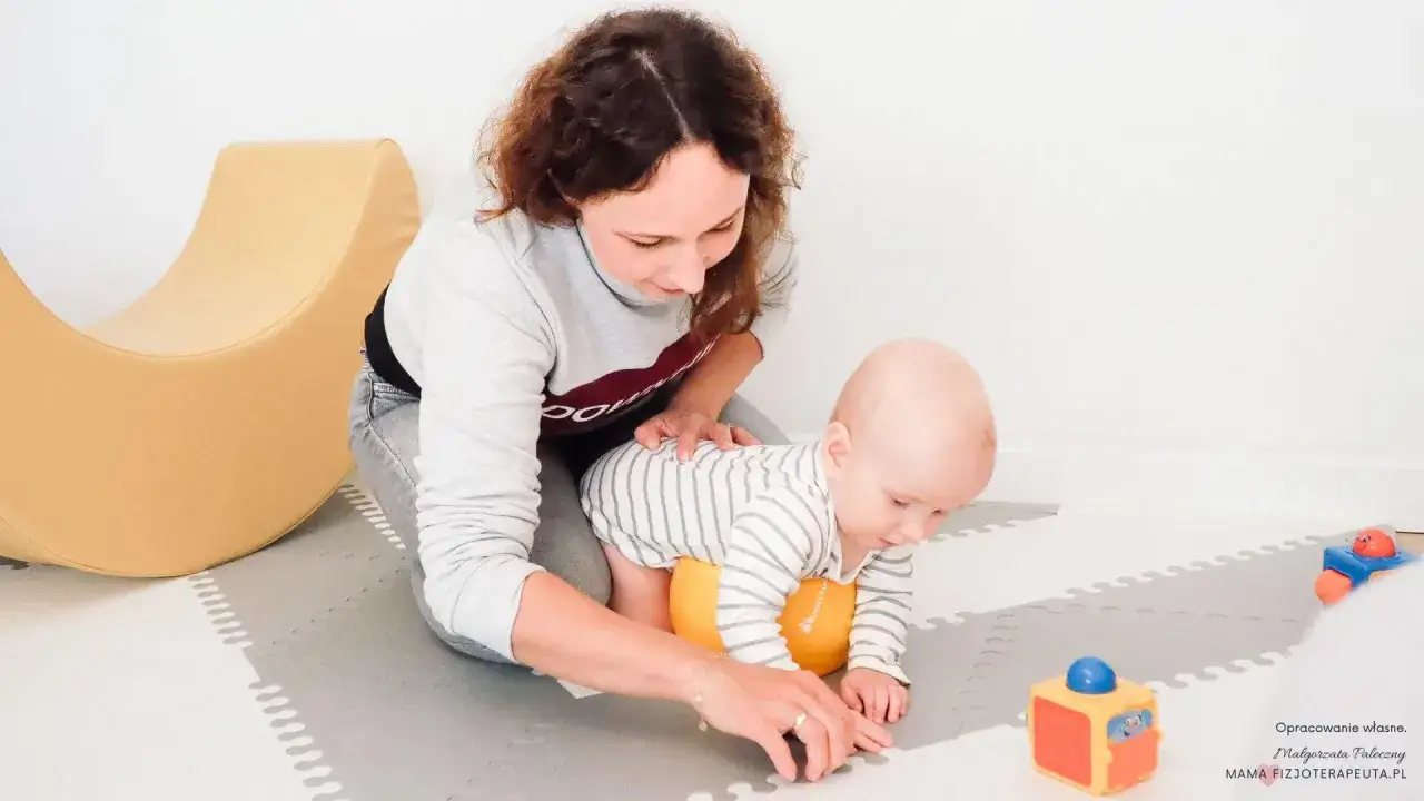 Mama wspiera dziecko w czworakowaniu, pomagając mu przejść przez 7 skok rozwojowy. Zabawa na macie z kolorowymi zabawkami.